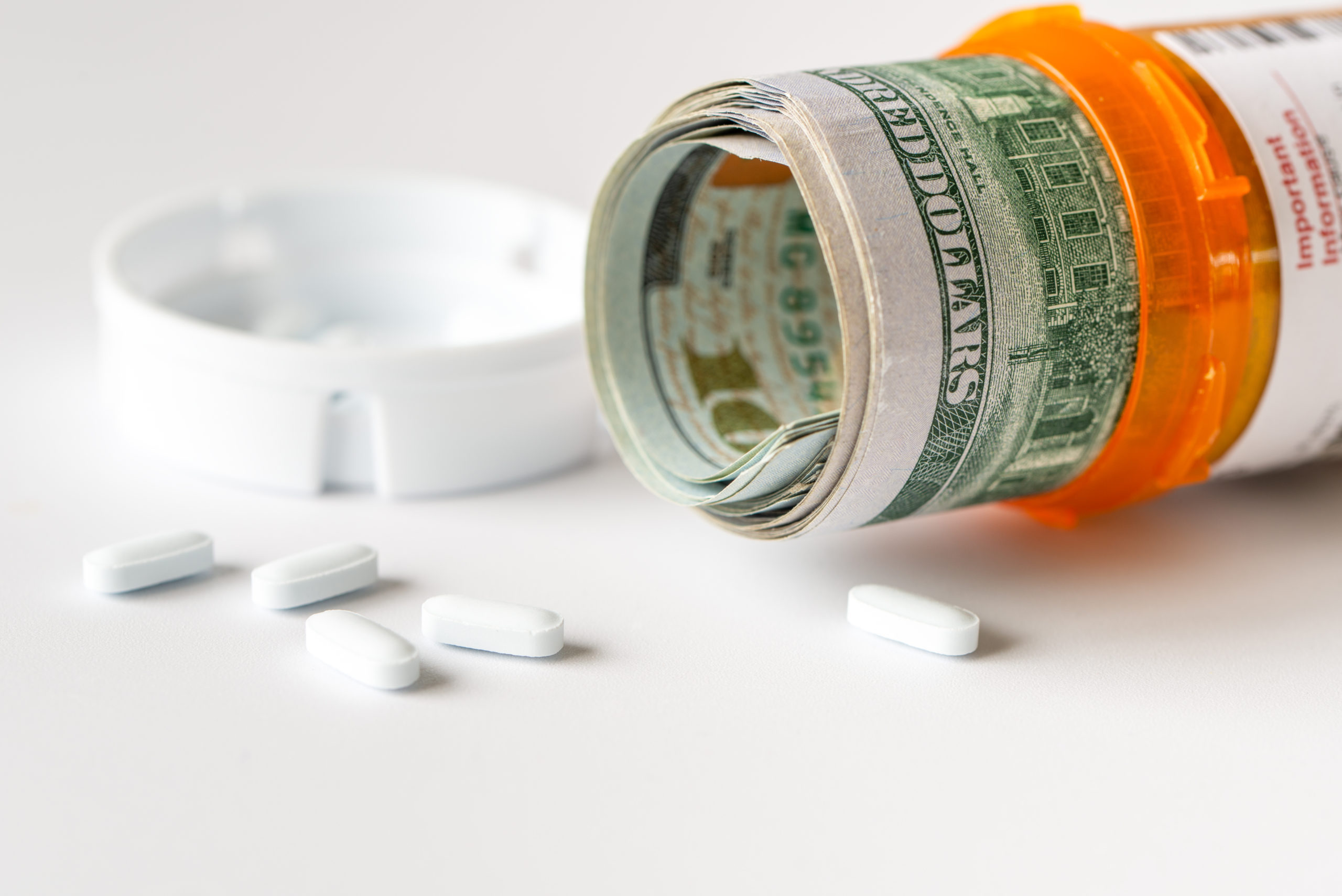 Opioid and Pharmacy Fraud Cases using US Dollars with white medicine pills spilling from bottle